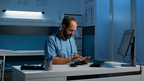 Portrait of young man using mobile phone while standing in office