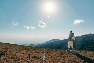 Rear view of man standing on mountain against sky