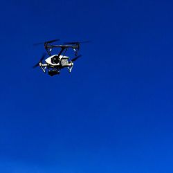 Low angle view of aircraft in flight against clear blue sky