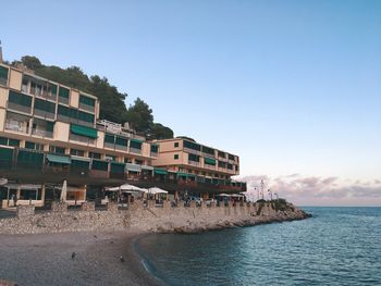 Buildings by sea against clear sky