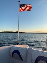 Flag on pole by sea against sky