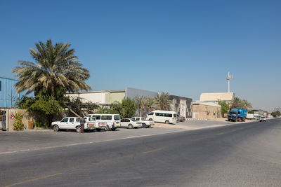 Cars on road by buildings against clear sky