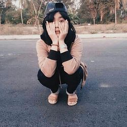 Young woman sitting on sidewalk