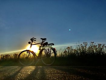 Bicycle on field against clear sky during sunset