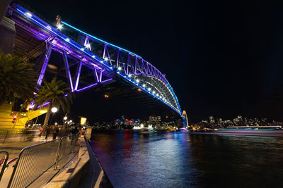 Illuminated bridge over river at night