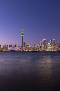 Illuminated buildings in city against clear sky