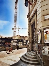 Bicycle by building in city against sky