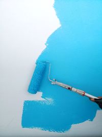 Close-up of hand holding blue over white background