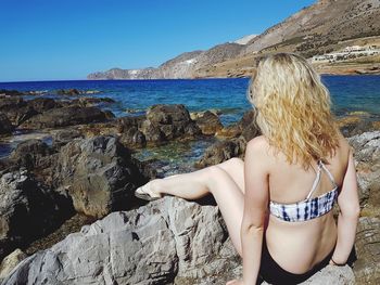 Rear view of woman at beach against clear sky