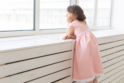 Side view of girl looking through window