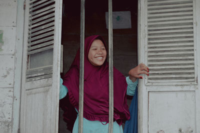 Portrait of young woman standing against wall