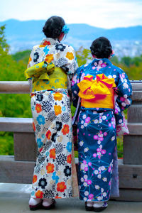 Rear view of women in kimono standing against railing