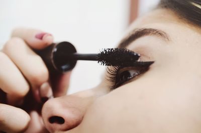 Close-up of woman using mascara