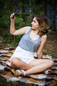 Beautiful teenager girl taking a selfie at the forest. using technology
