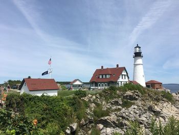 Lighthouse amidst plants and buildings against sky