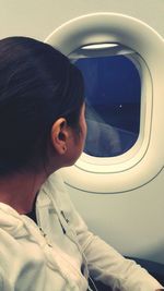 Side view of young woman looking through window