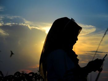 Silhouette woman against orange sky during sunset