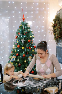 Mother playing with christmas tree at home