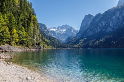 Scenic view of lake and mountains against clear blue sky