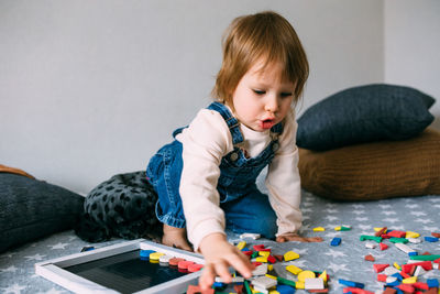 Child plays at home an educational game with a multi-colored magnetic puzzle