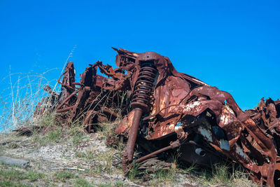 Low angle view of abandoned rusty against clear blue sky
