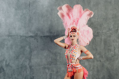 Portrait of woman standing against pink wall