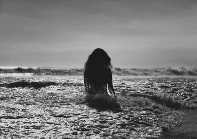 Rear view of woman on sea shore against sky