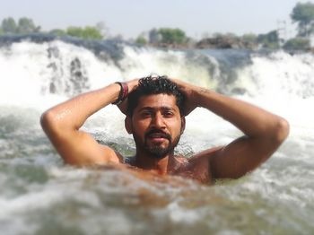 Portrait of shirtless young man in sea