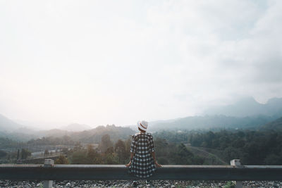Rear view of man standing on mountain against sky