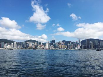 Sea by buildings against sky in city