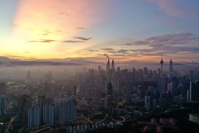 Aerial view of buildings in city at sunset