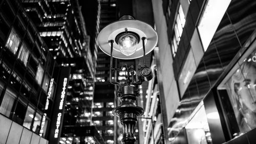 Low angle view of illuminated gas light amidst buildings at night