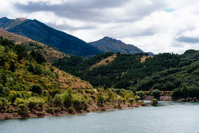 Scenic view of mountains and river against cloudy sky