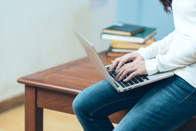 Midsection of man using mobile phone while sitting on table