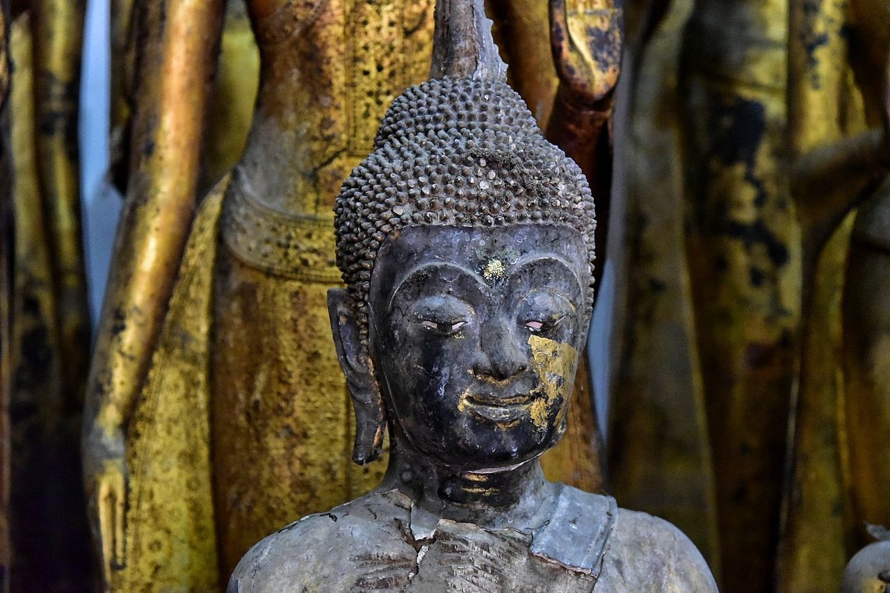 CLOSE-UP OF BUDDHA STATUE AGAINST TEMPLE