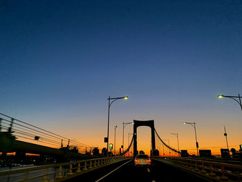 Vehicles on road against sky during sunset