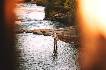 MAN STANDING BY RIVER AGAINST SKY