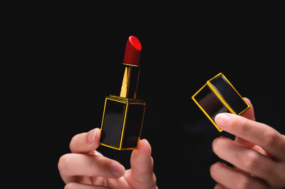 Close-up of hand holding electronic cigarette against black background