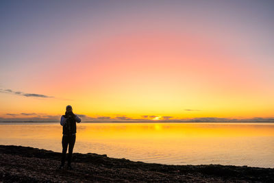 Man standing on beach against sky during sunset
