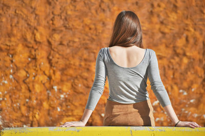 Rear view of young woman leaning on railing