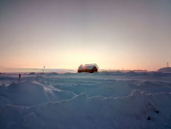 Car on snow covered landscape against sky during sunset