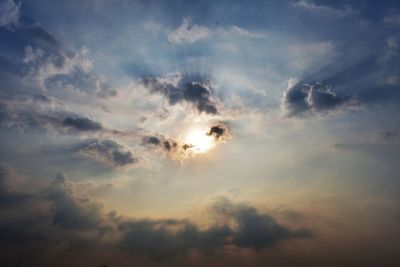 Low angle view of sun behind clouds