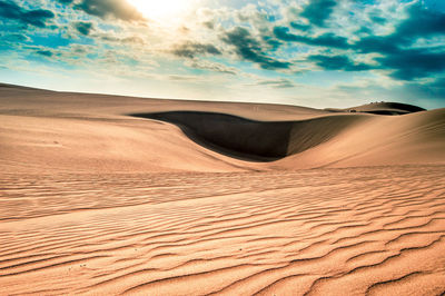 Sand dunes in desert against sky