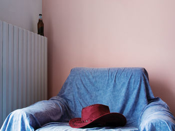 Close-up of a hat on armchair against the wall