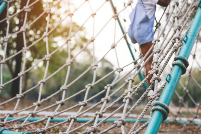 Low section of man standing on rope fence