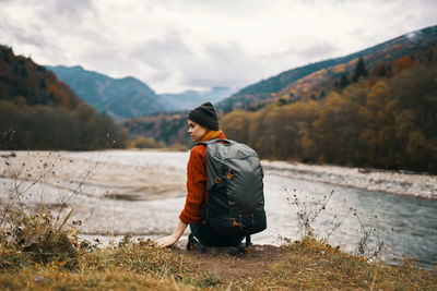 Rear view of man looking at lake against mountain