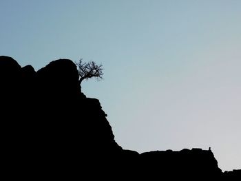 Low angle view of silhouette rocks against clear sky