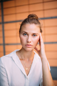 Portrait of beautiful young woman touching forehead