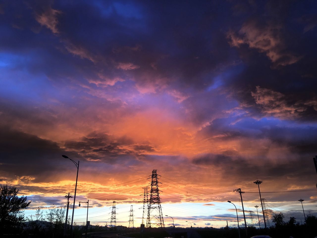 sunset, sky, silhouette, cloud - sky, beauty in nature, tranquility, scenics, orange color, tranquil scene, dramatic sky, nature, cloudy, low angle view, cloud, idyllic, street light, electricity pylon, landscape, dusk, outdoors