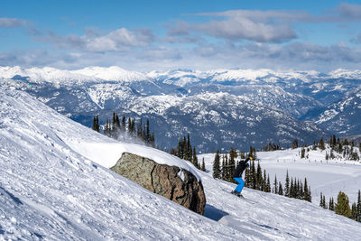 Man snowboarding on snowcapped mountains against sky